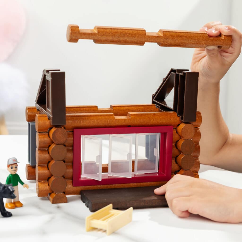 Photo of someone building the roof of the Lincoln Logs Adventure Pod Cabin