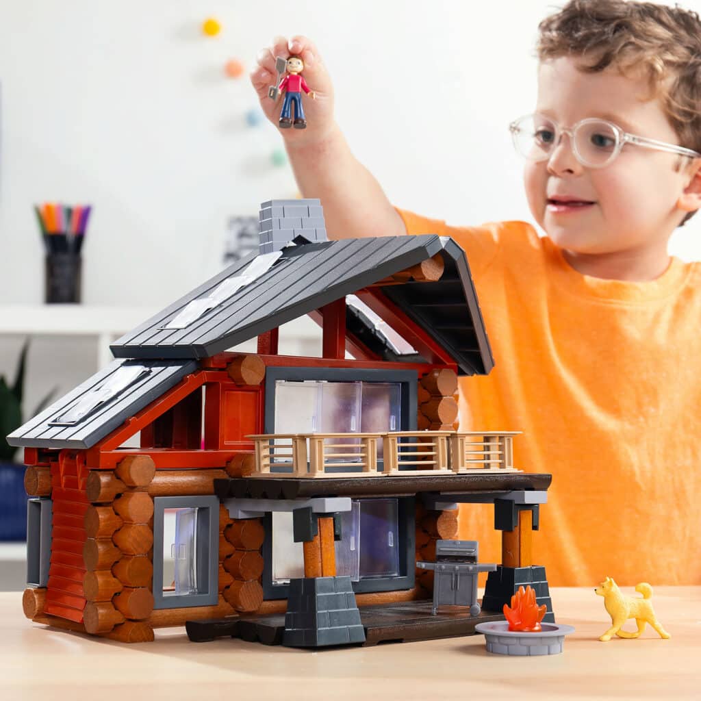Child playing with the fully built Lincoln Logs Beechwood Retreat featuring the toy man in the childs hand