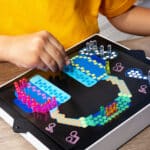 Little kid playing with the Lite-Brite Classic, Bold & Bright Edition making a headphones design