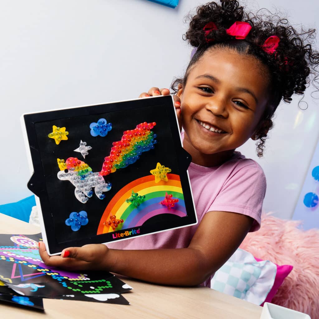 Little girl showing off her unicorn design on the Lite-Brite Classic, Bold & Bright Edition