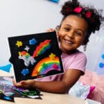 Little girl showing off her unicorn design on the Lite-Brite Classic, Bold & Bright Edition