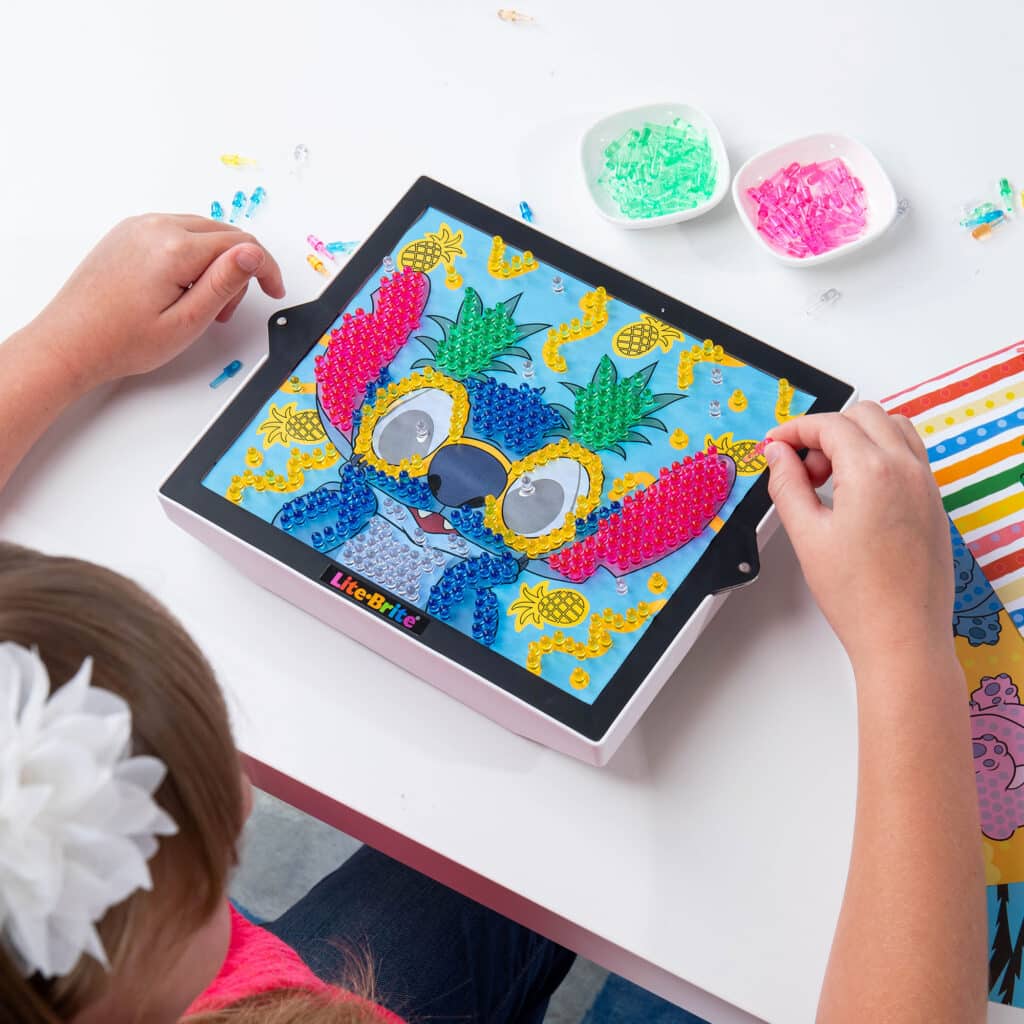 Birds eye view of a little girl playing with the Lite-Brite ColorPOP! Stitch