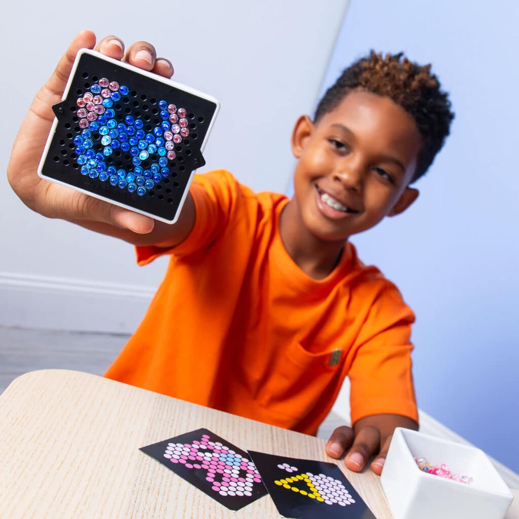 Little boy showing off his completed Lite Brite Mini, Stitch