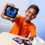 Little boy showing off his completed Lite Brite Mini, Stitch