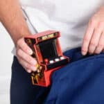 Someone putting the Arcade Classics Mortal Kombat Handheld Arcade Game in a backpack