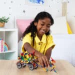 Little girl playing with a horse drawn carriage built from the K'NEX 80 Model Building Set
