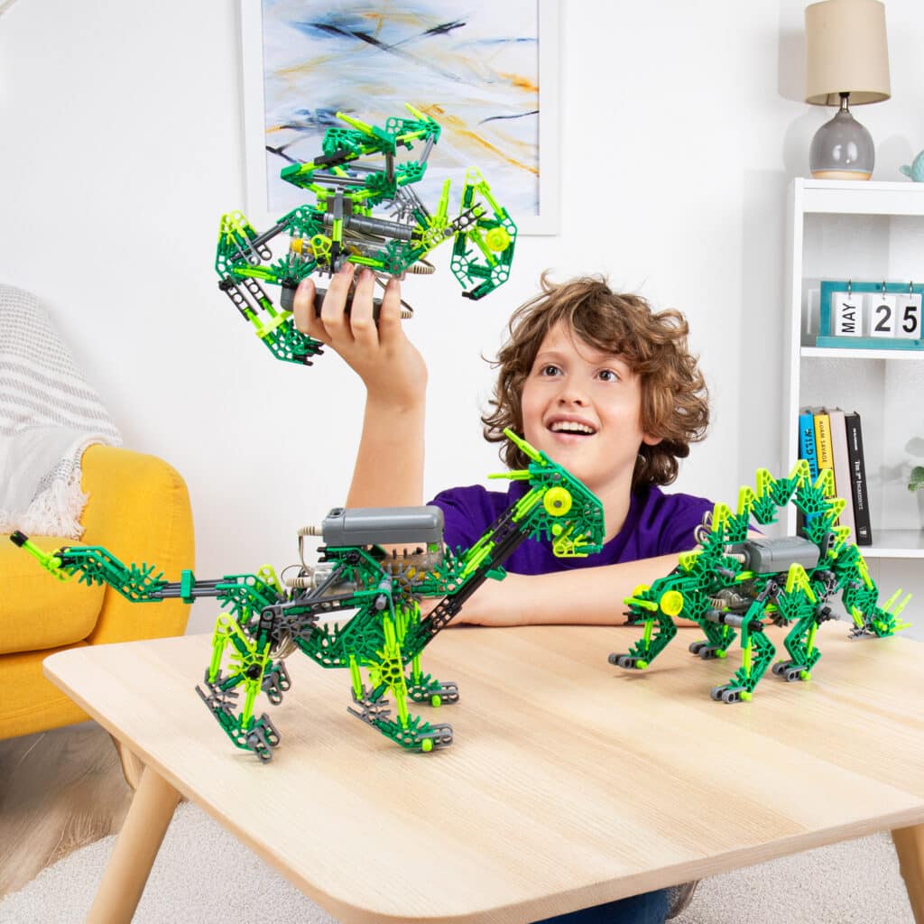 Little boy playing with 3 dinos built from the K'NEX Dynamic Dinos 6-in-1 Building Set