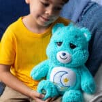 Little boy holding the Care Bears Medium Cozy Bedtime Bear Plush