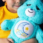 Little kid holding the Care Bears Medium Cozy Bedtime Bear Plush