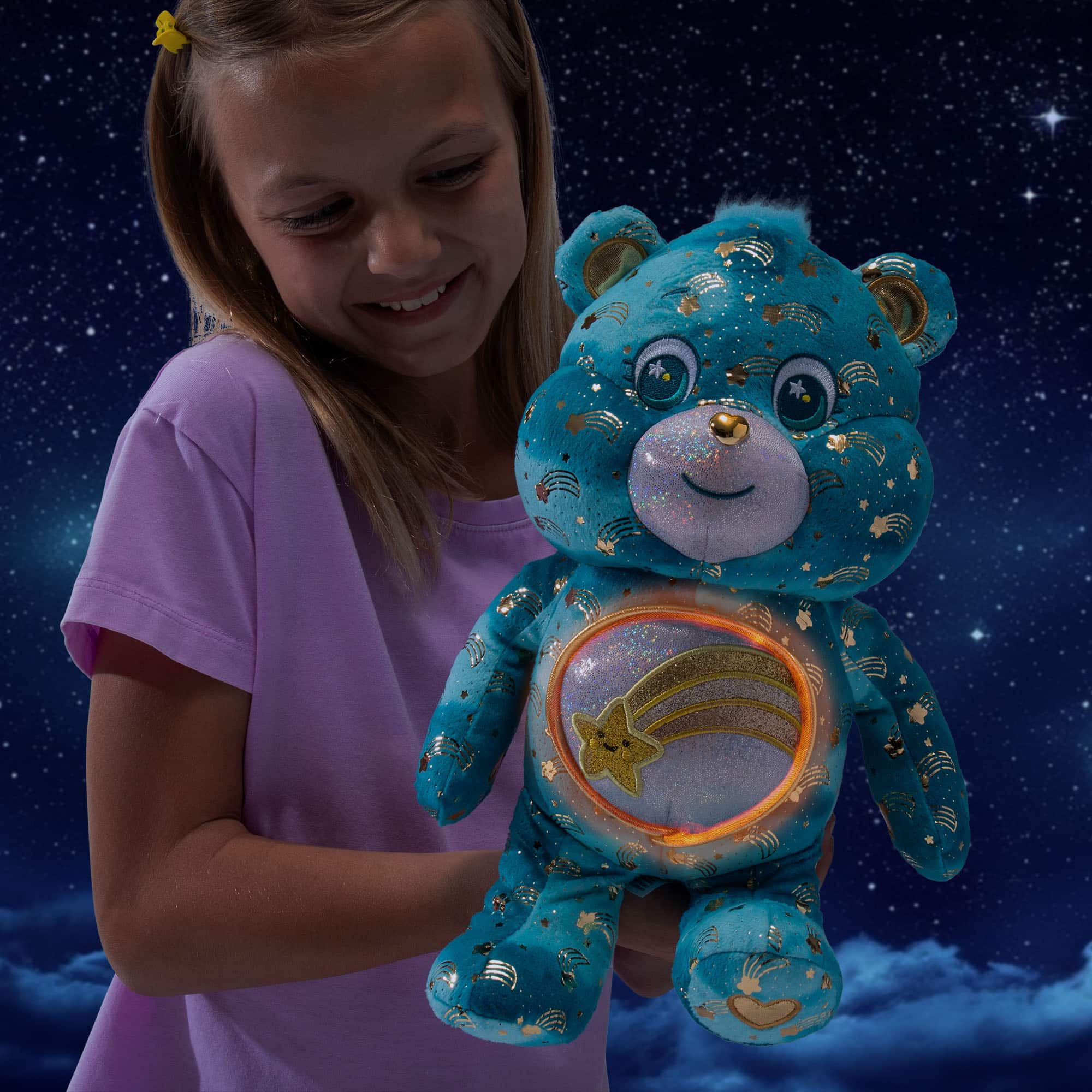 Little girl playing with Care Bears - 14" Medium Plush - Collector's Edition Wish Bear. Shot in the dark displaying the glow in the dark Belly Badge.