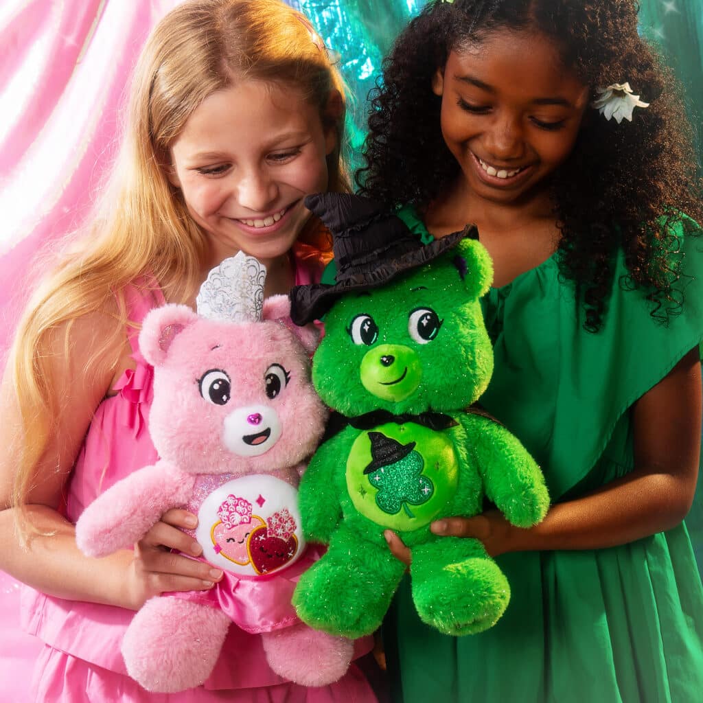 Little girls playing with the Love-a-Lot Bear as Glinda and Good Luck Bear as Elphaba included in the Care Bears x Wicked 2-Pack Boxed Set