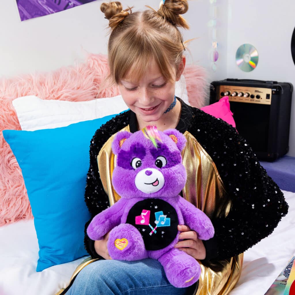 Child playing with Care Bears - 14" Medium Plush - Rock-a-Lot Share Bear